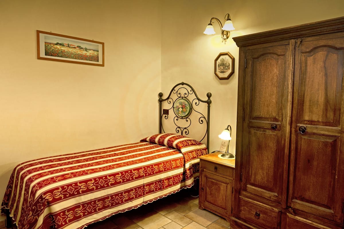 Een slaapkamer met een bed, nachtkastje, kledingkast en wandlampen.