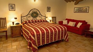 Een slaapkamer met een groot bed, twee nachtkastjes met lampen, een rode bank en ingelijste foto's aan de wand.