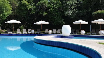 Una piscina al aire libre de temporada, sombrillas