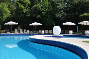 Piscine extérieure en saison, parasols, chaises longues