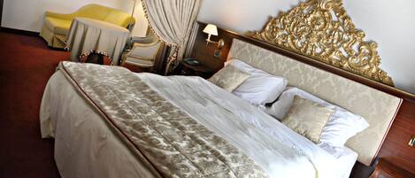 A hotel room with a large bed, a bedside table, a lamp, and a chair.