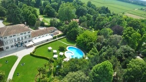 An aerial view of a large estate with a swimming pool, manicured lawns, and a grand building with a tiled roof. - Hotel Villa Condulmer (Mogliano Veneto)