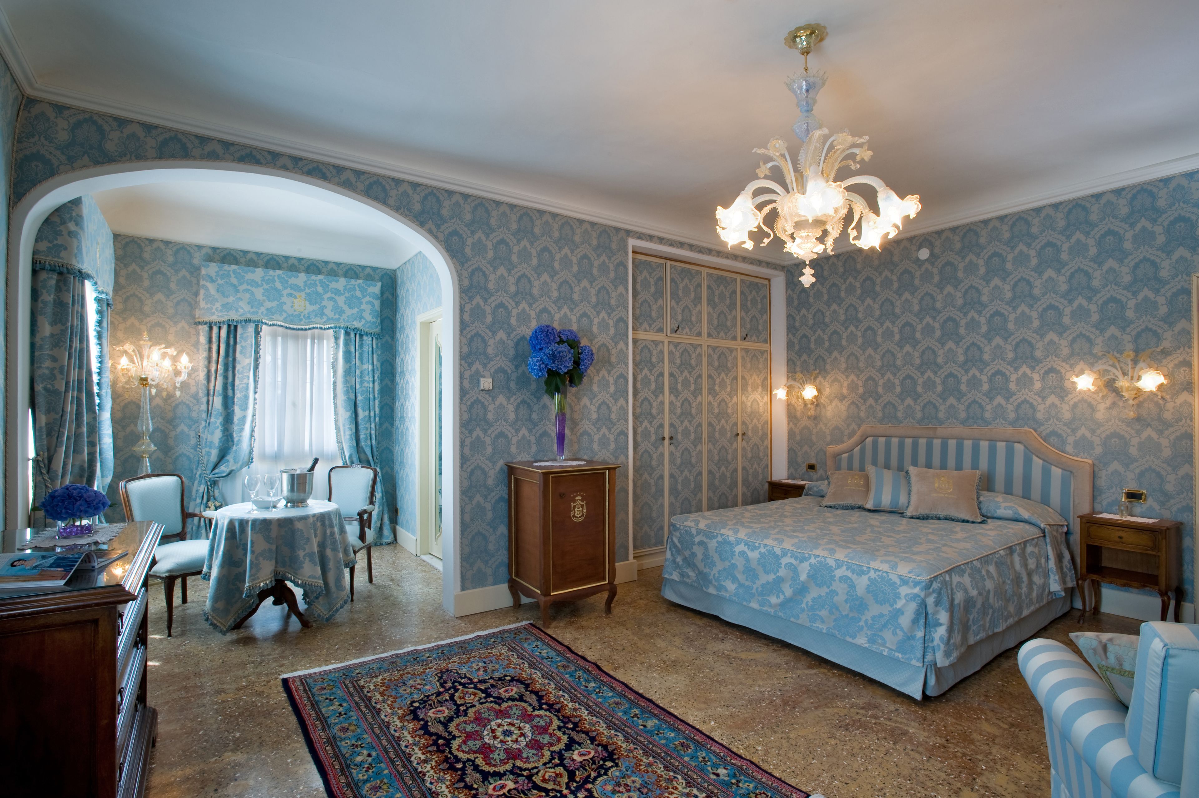 Un dormitorio con cama, candelabro, escritorio y una silla.