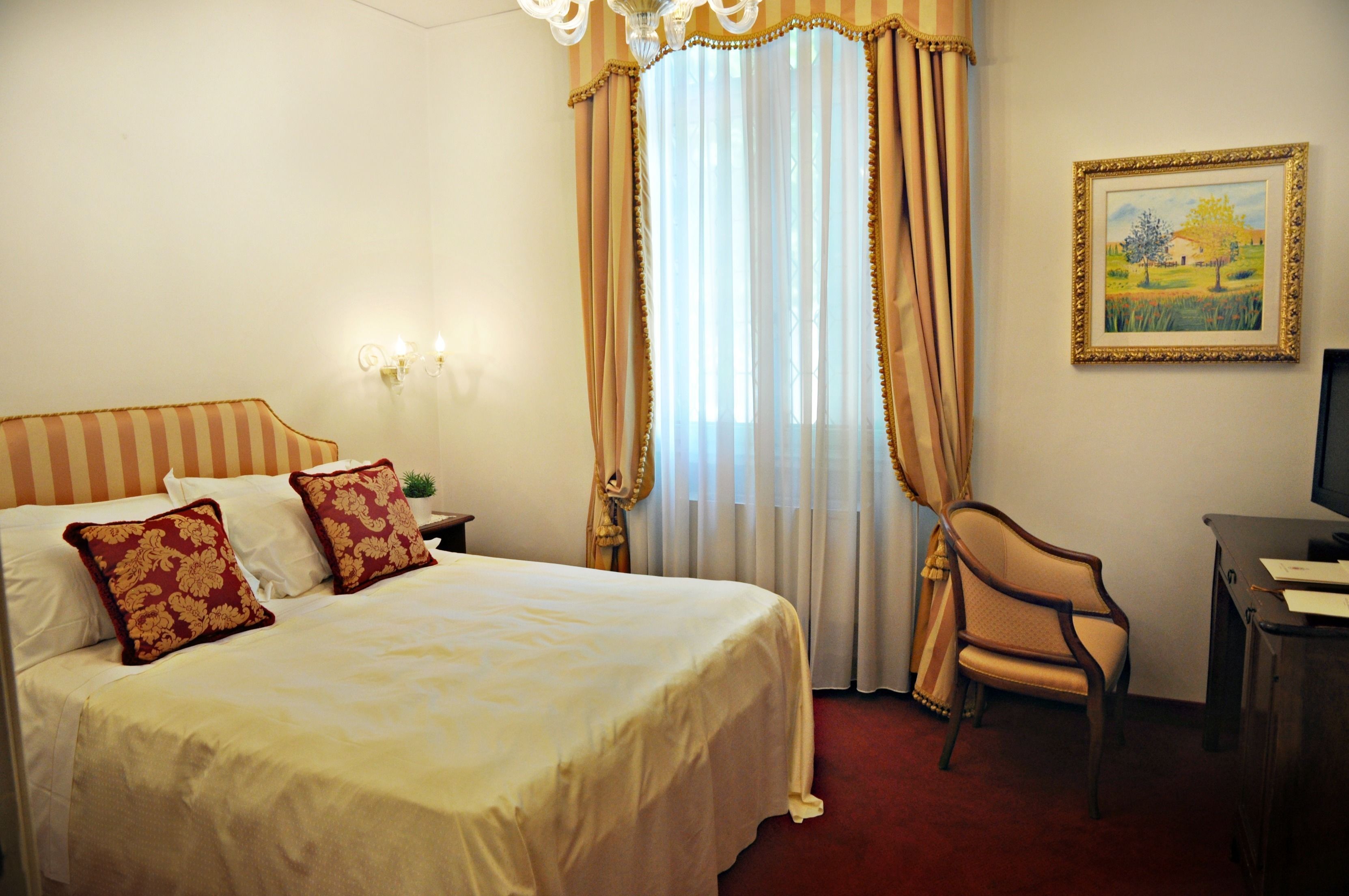 Habitación de hotel con una cama grande, una silla, un escritorio y un cuadro en la pared.