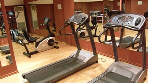 Un gimnasio con cintas de correr, bicicletas estáticas y elípticas.