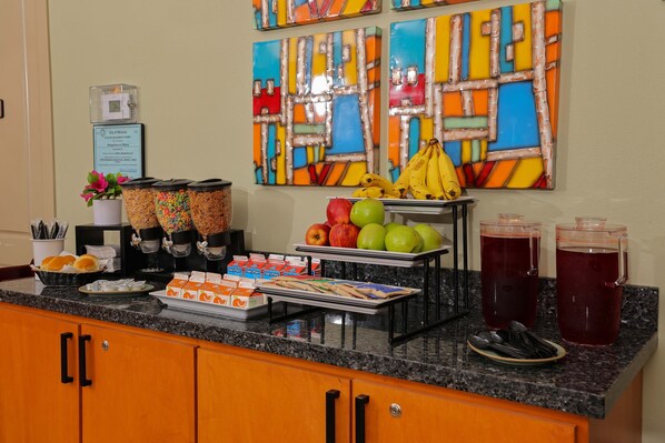 A breakfast buffet with fruits, pastries, and beverages.