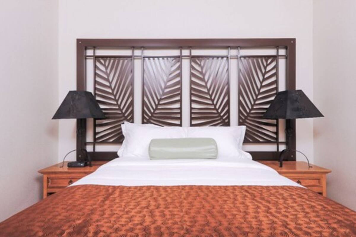 A hotel room with a bed, two bedside tables, and a decorative headboard.