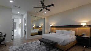 A modern hotel room with a large bed, bedside tables, a desk, and a ceiling fan. - The Bungalows on Shary, Mission-McAllen (Mission)