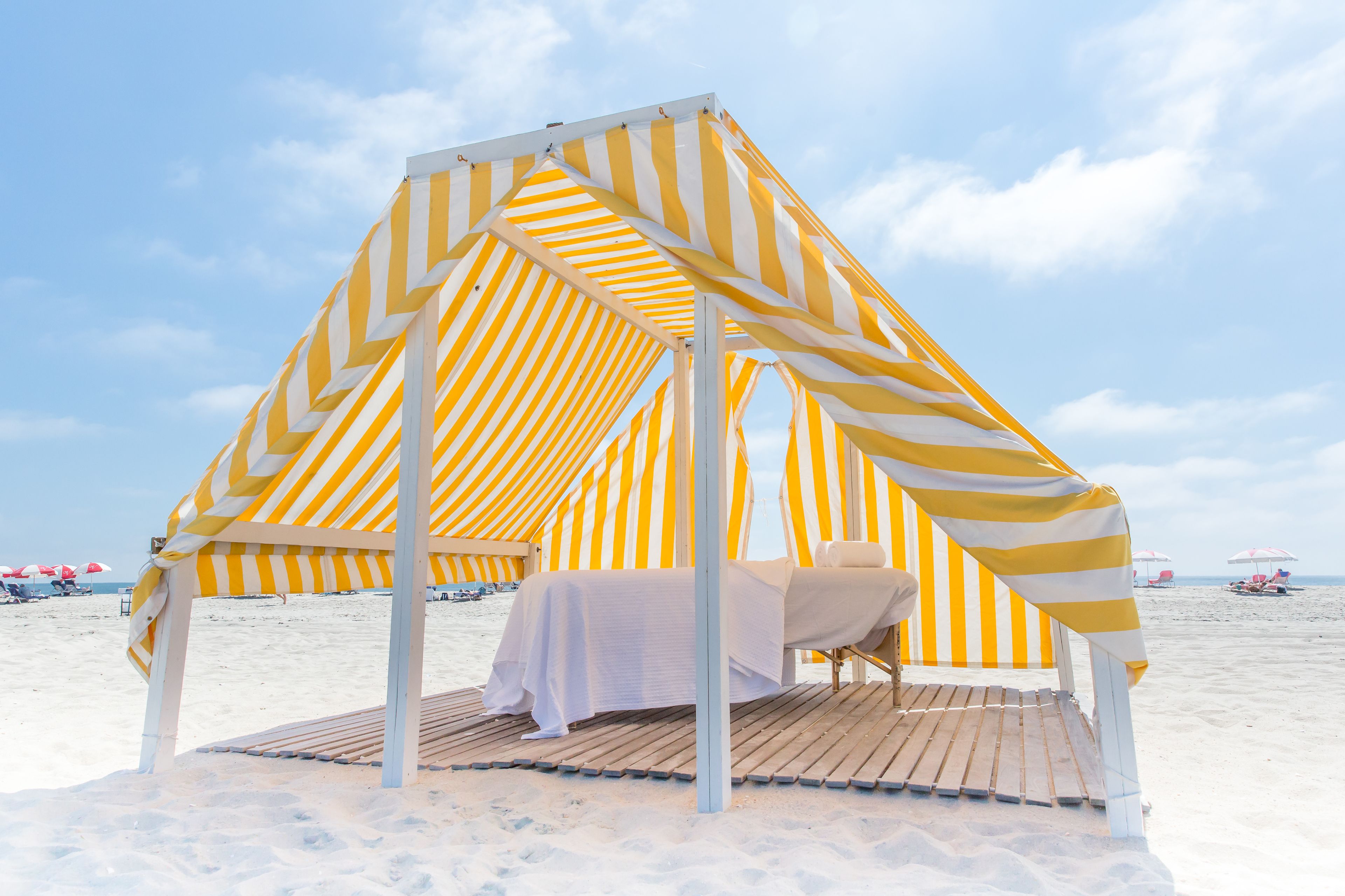 Una cabaña en la playa con un toldo a rayas y una mesa preparada para dos.