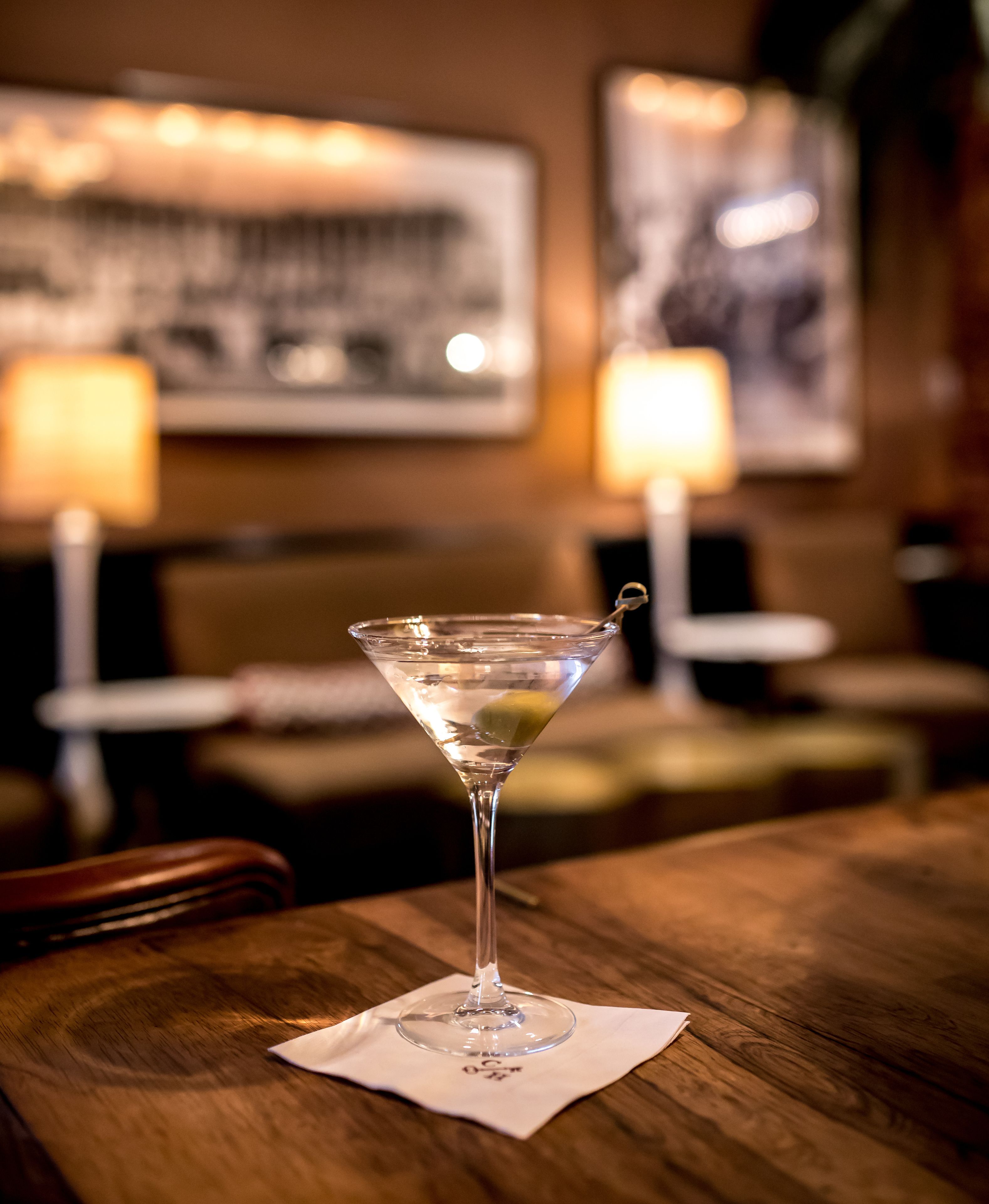 A martini glass on a wooden table with a white napkin underneath.