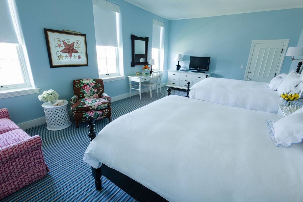A bedroom with a large bed, a desk, a chair, a television, and a window.
