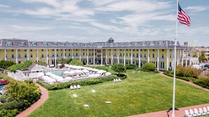 A large hotel with a swimming pool, outdoor seating, and a flag.
