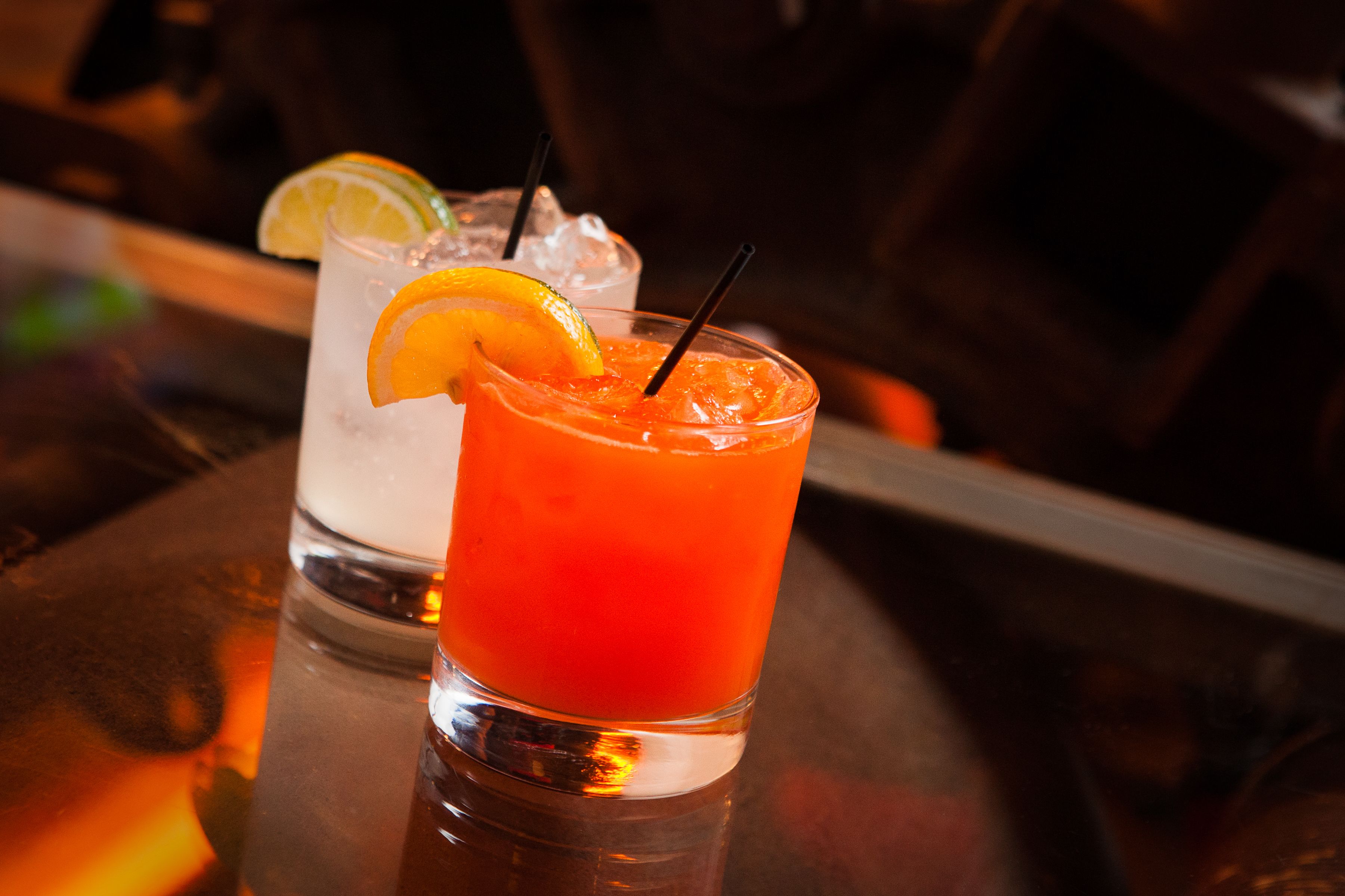 Two glasses of cocktails on a bar counter.