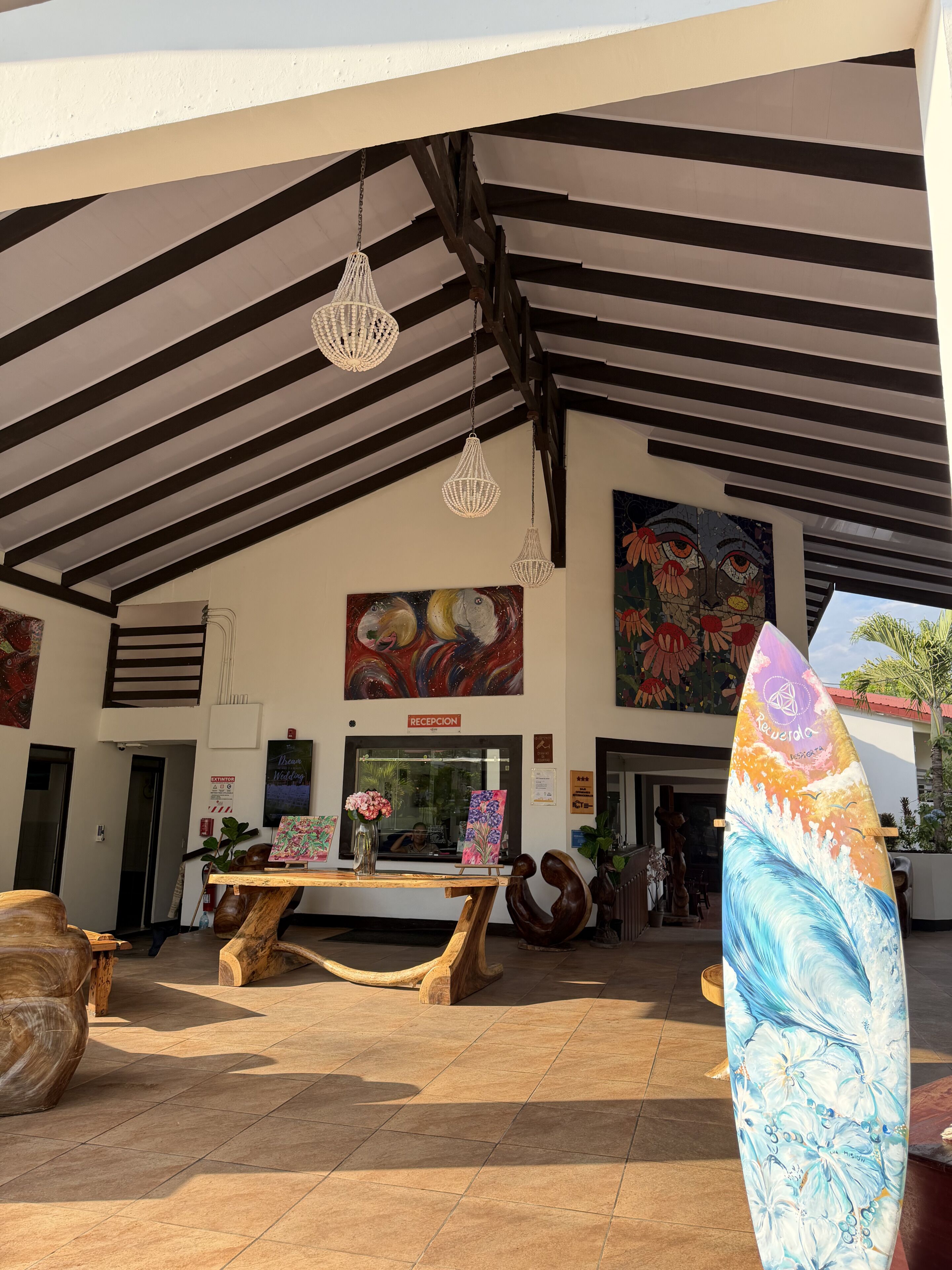 A reception area with a reception desk, a painting, and a surfboard.