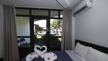 Una habitación de hotel con una cama, un ventanal grande y un equipo de aire acondicionado.