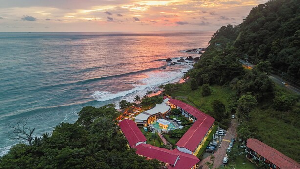 An aerial view of a resort with a pool, a red-roofed building, and a beach. - Terraza Del Pacifico Hotel (Jacó)