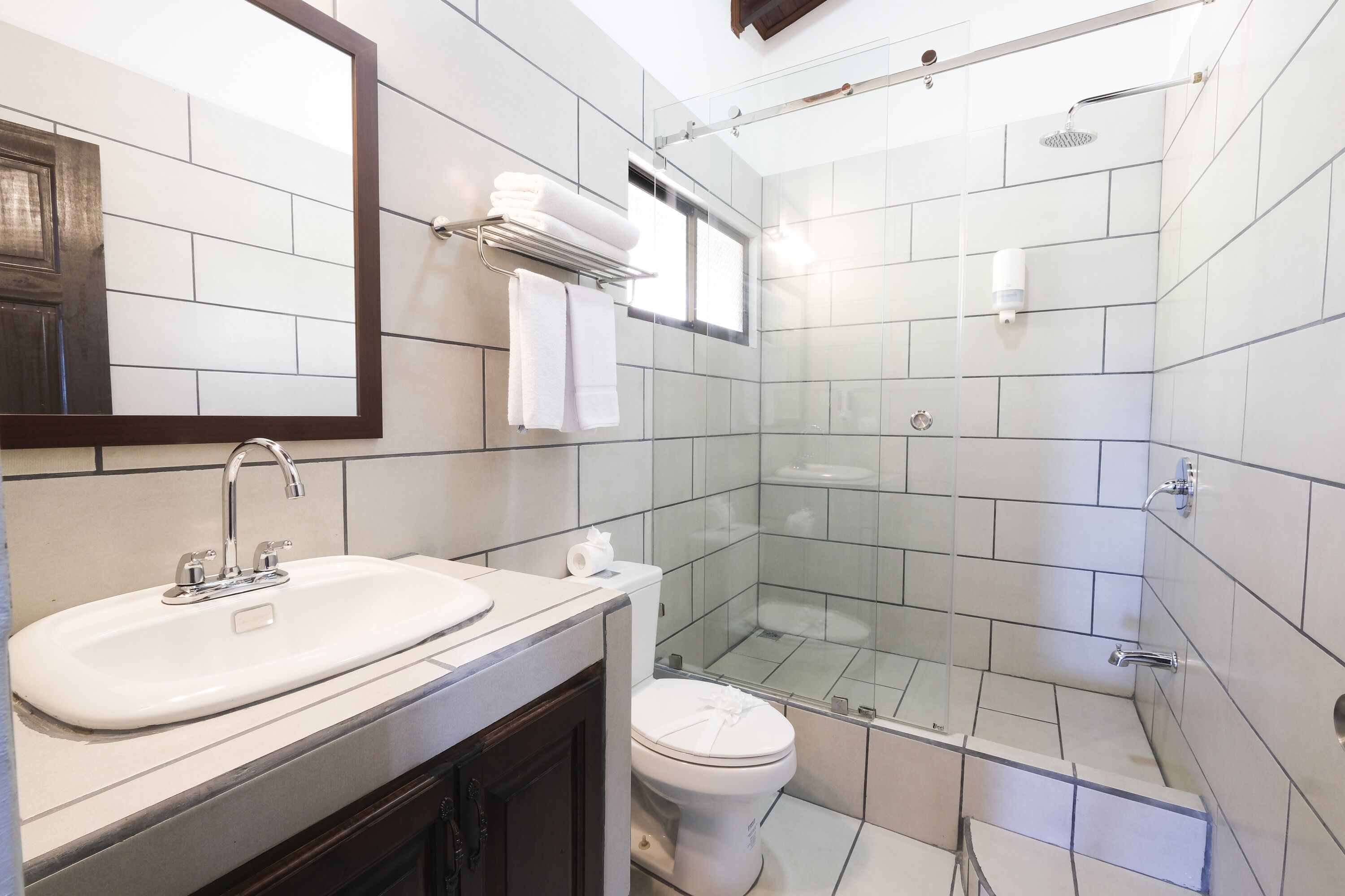 A modern bathroom with a sink, mirror, and glass-enclosed shower.