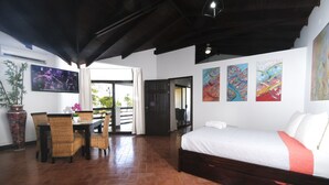 A room with a bed, a dining table with chairs, a TV, and artwork on the walls. - Terraza Del Pacifico Hotel (Jacó)