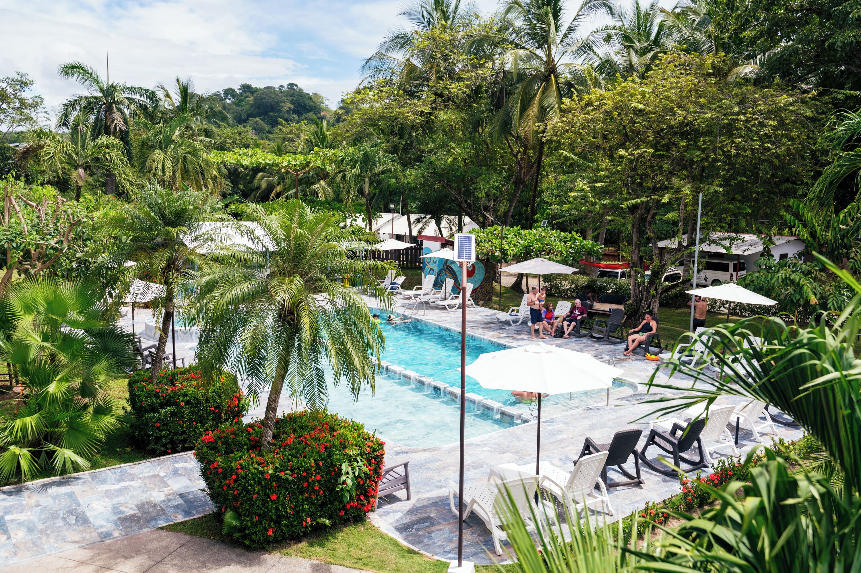 A pool area with lounge chairs, umbrellas, and a view of the surrounding greenery.