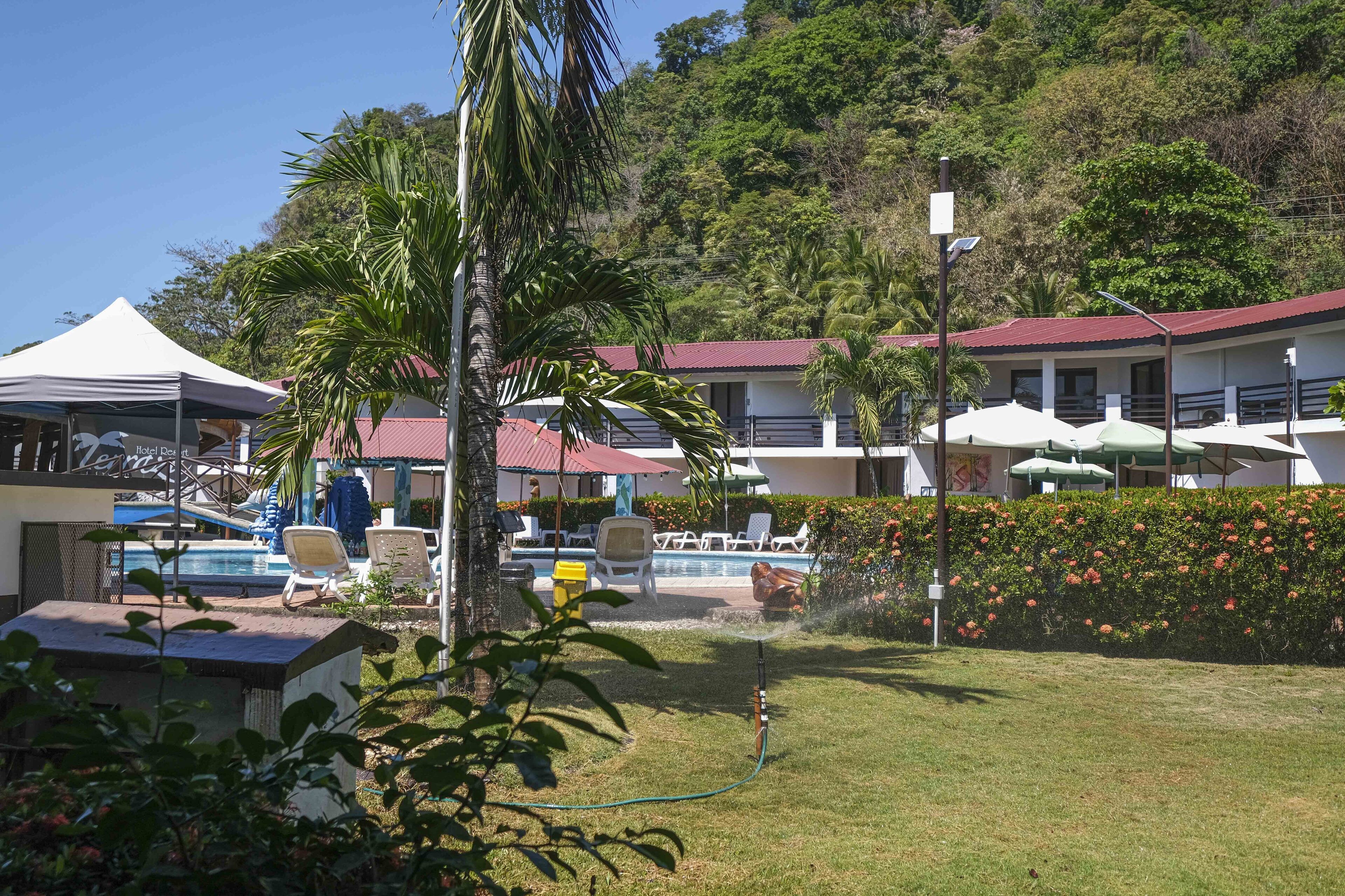 A resort with a swimming pool, lounge chairs, and a covered area.