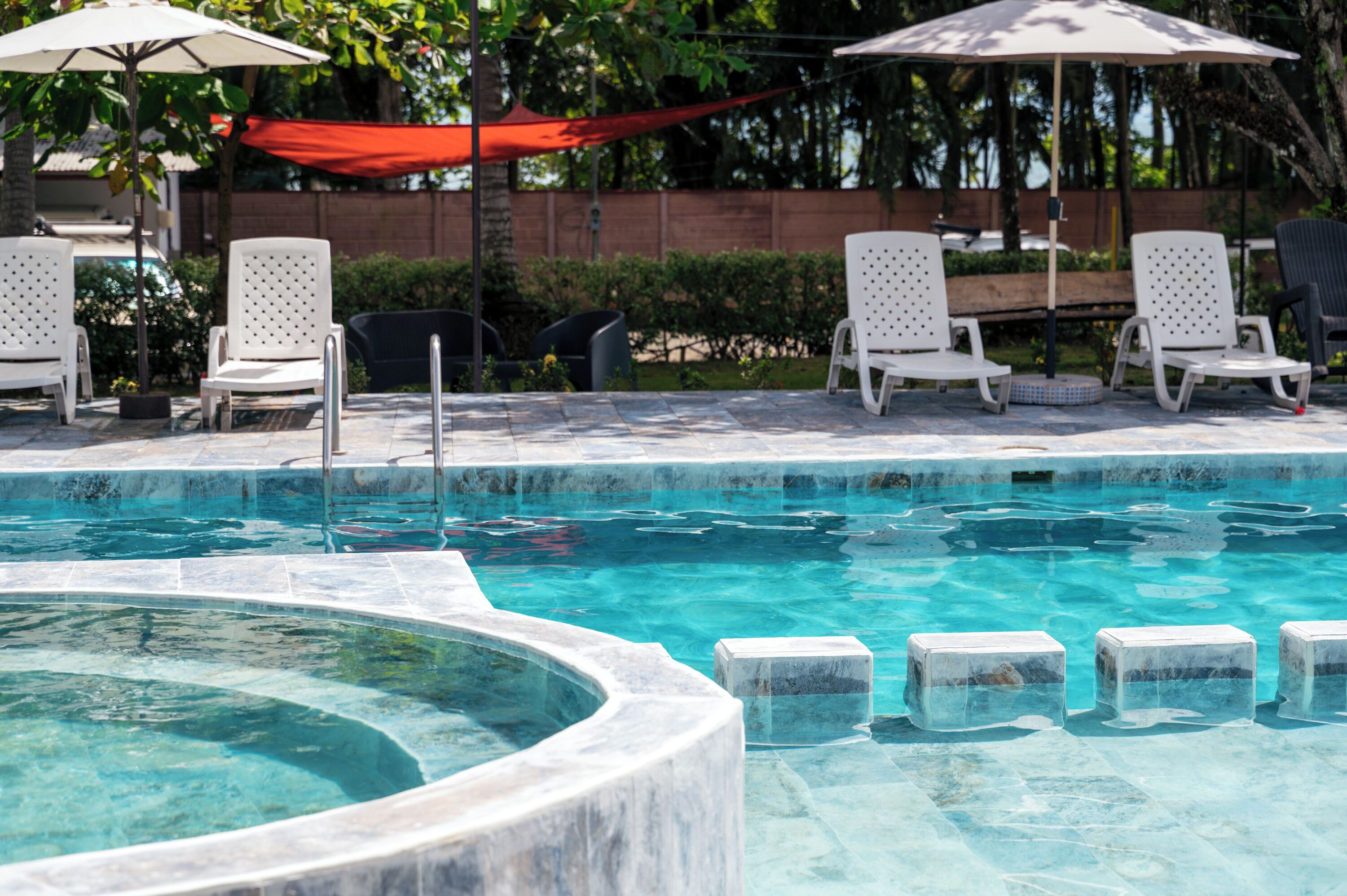 A pool area with lounge chairs and umbrellas.