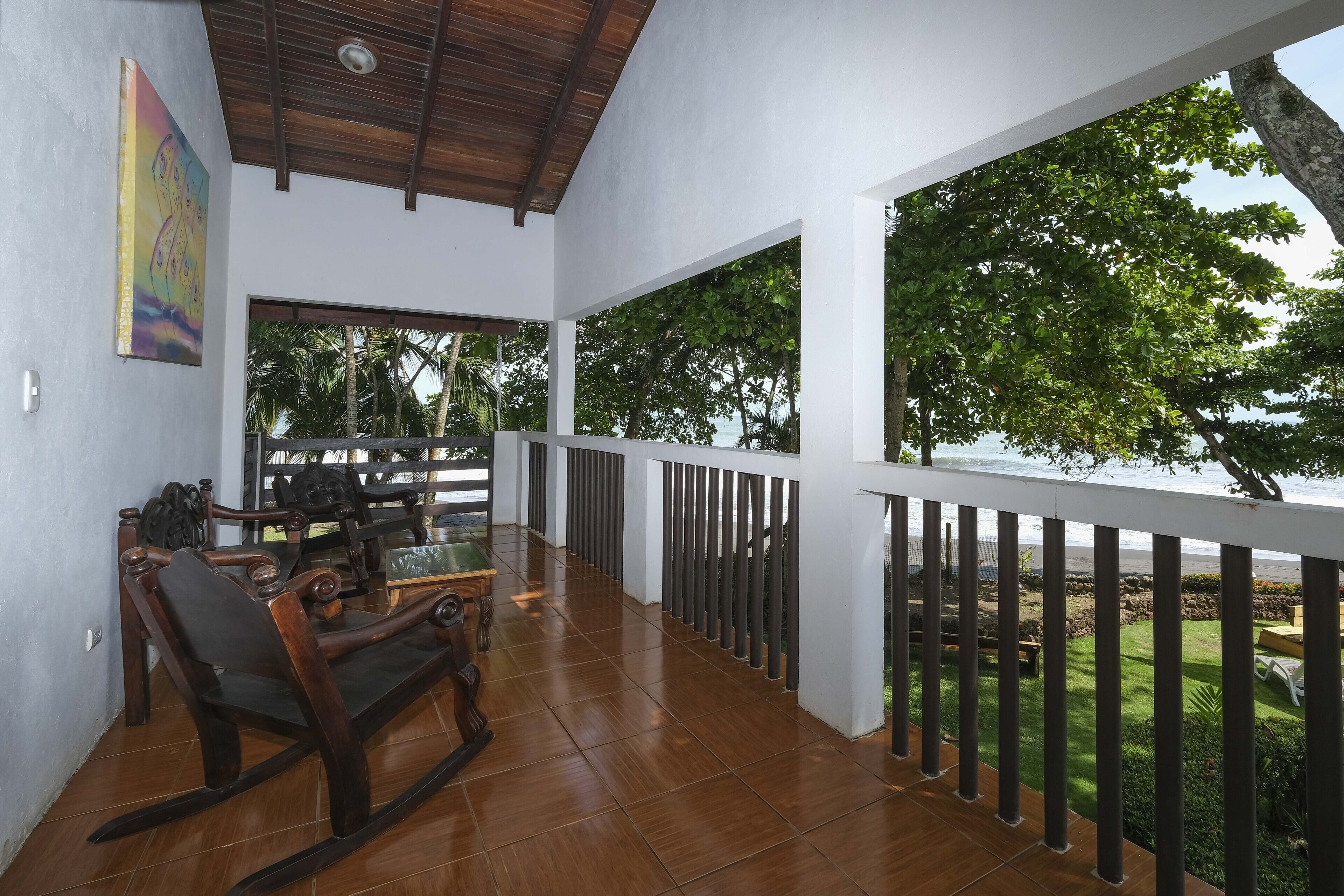 A balcony with a wooden table and chairs, a view of the sea, and a railing.