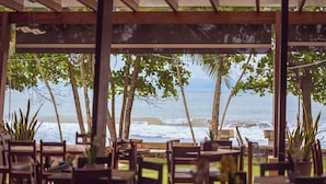 An outdoor seating area with tables and chairs, overlooking the ocean. - Terraza Del Pacifico Hotel (Jacó)