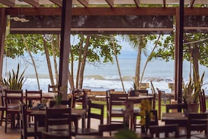 An outdoor seating area with tables and chairs, overlooking the ocean.