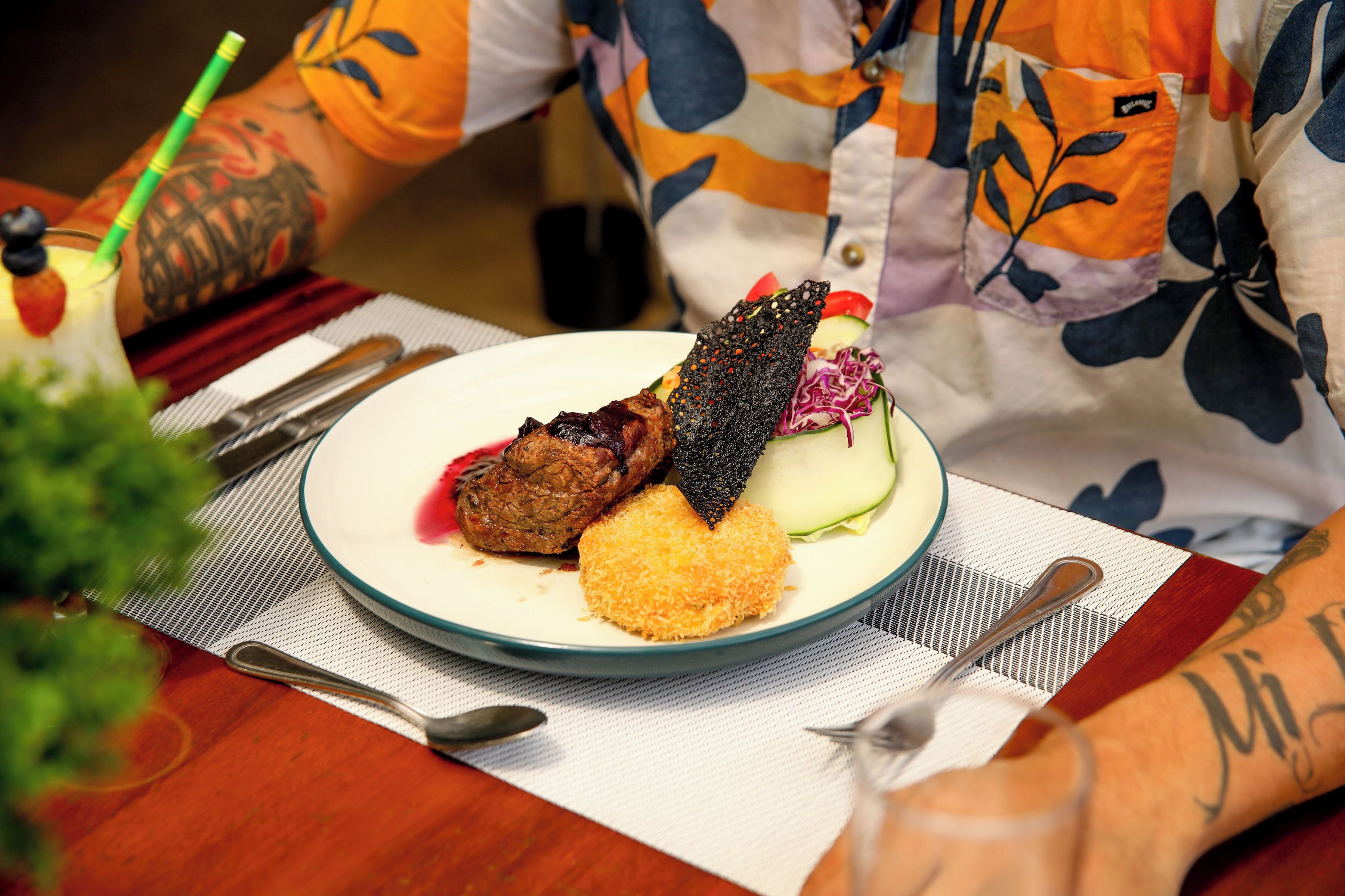 A plate of food with a variety of items including a piece of meat, a breaded item, and a vegetable salad.