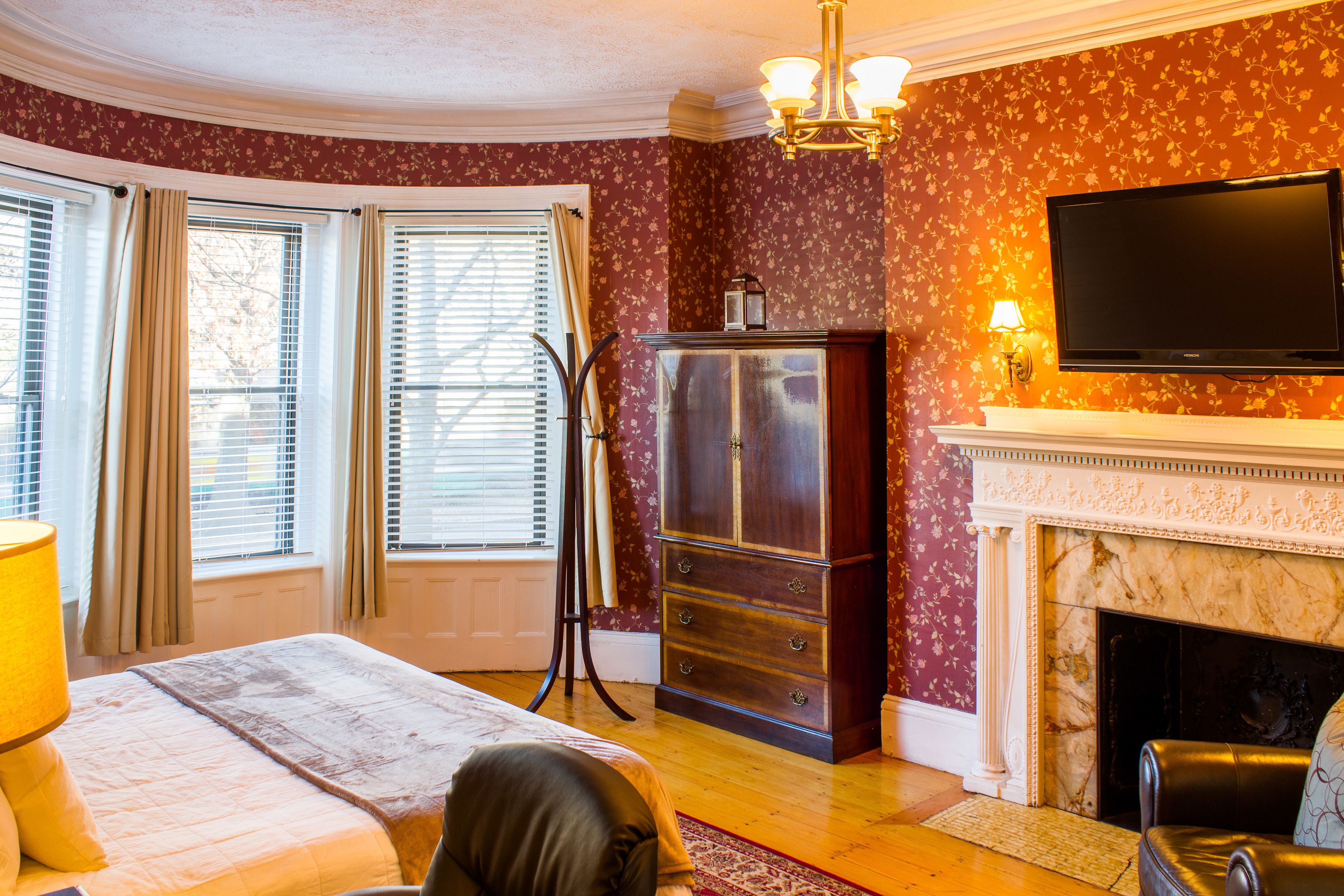 Ein Schlafzimmer mit einem Bett, einem Schminktisch, einem Fernseher und einem Kamin.