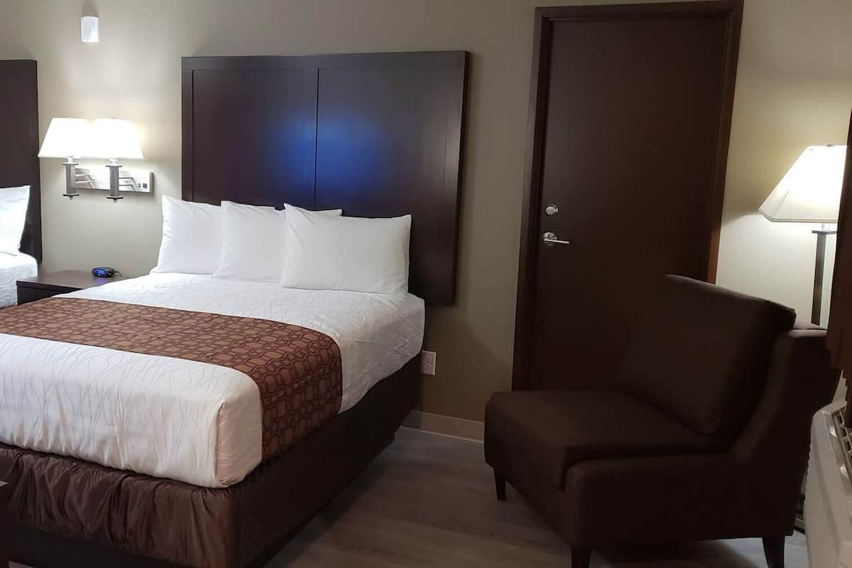Ein Hotelzimmer mit zwei Betten, einem Schreibtisch, einem Stuhl und einer Tür.