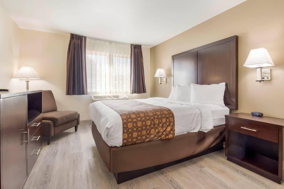 Ein Hotelzimmer mit einem Bett, Nachttischen, einem Schreibtisch und einem Sessel.