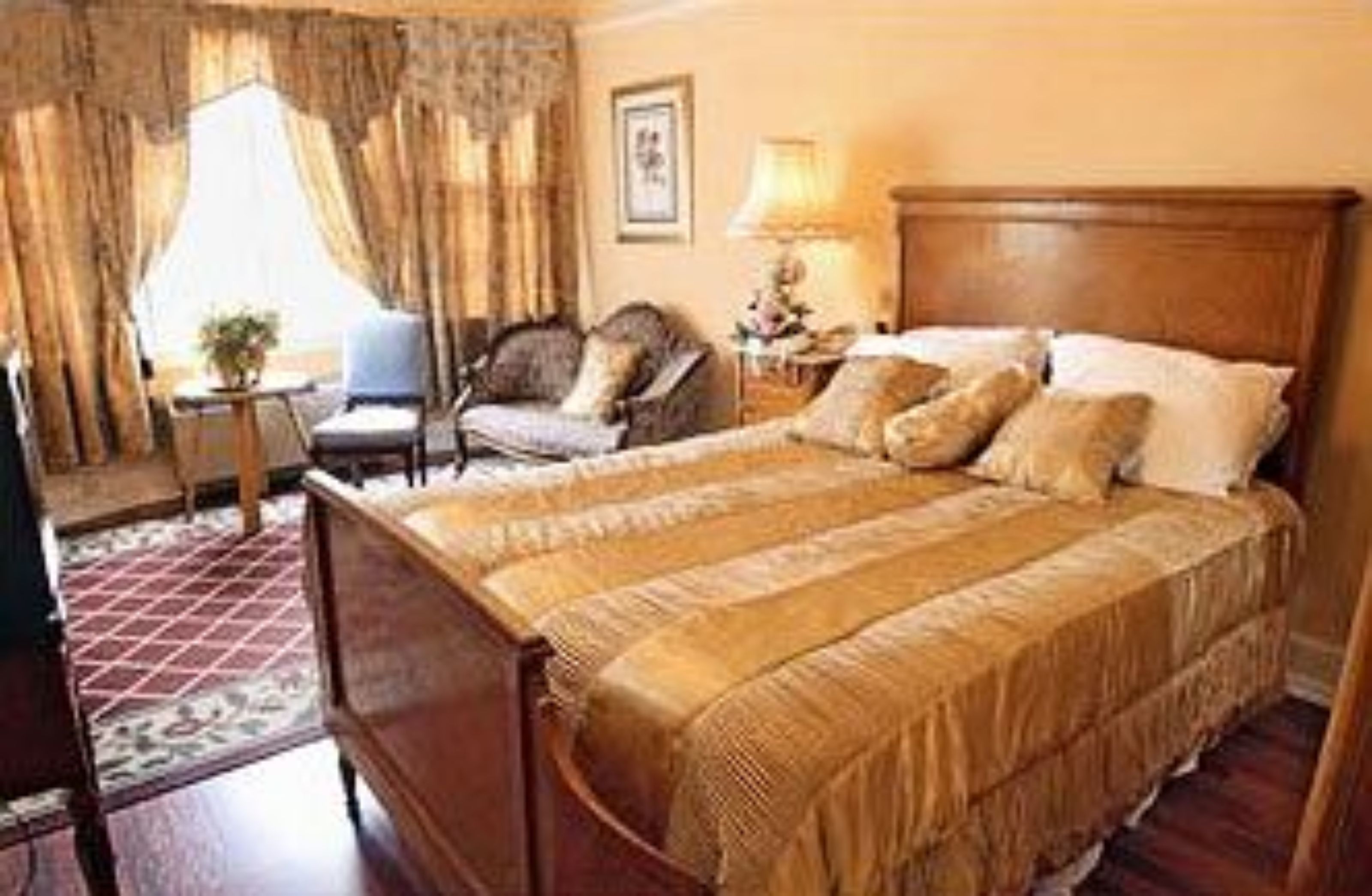 Una habitación de hotel con una cama grande, una silla, una mesita y una lámpara.