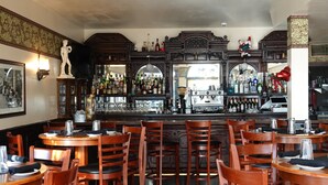 Zona de bar con muebles de madera, un espejo grande y diversas botellas.