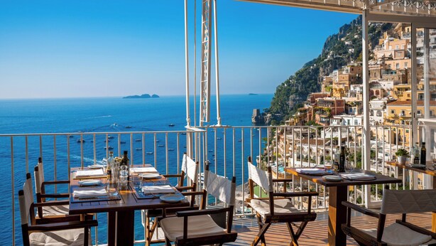A terrace with tables and chairs, overlooking a coastal town and the sea. - Hotel L'Ancora (Positano)