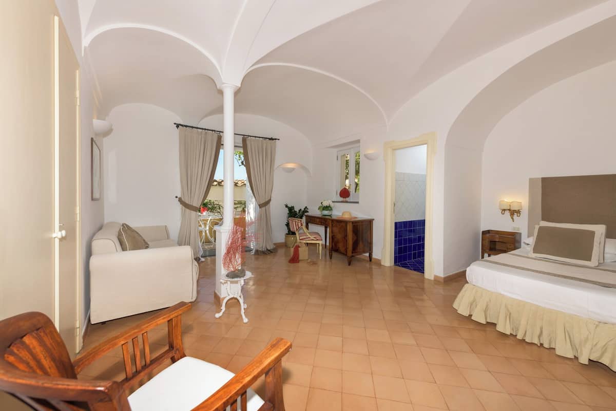 A hotel room with a bed, a desk, a chair, and a view of the outside.
