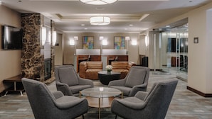 Eine Lobby mit Ledersofas, einem Glastisch und einem Fernseher links.