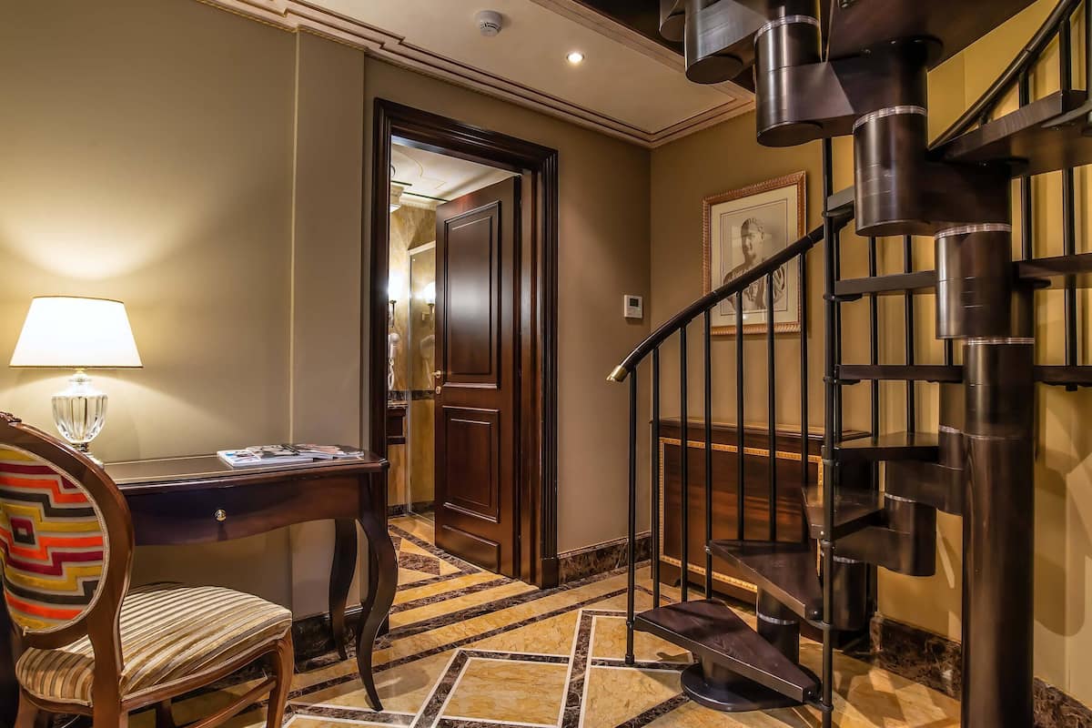 Ein Hotelzimmer mit Schreibtisch, Stuhl, Lampe und einer Wendeltreppe.