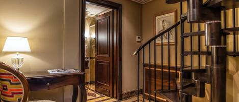 Une chambre d’hôtel équipée d’un bureau, d’une chaise, d’une lampe et d’un escalier en colimaçon.