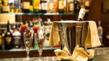 A bar setting with two champagne flutes and a bottle of champagne on a marble counter.