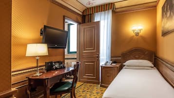 Ein Hotelzimmer mit Bett, Schreibtisch mit Lampe, Fernseher und Telefon.