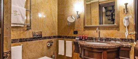A bathroom with a marble floor, a sink with a vanity, a toilet, a bidet, and towels hanging on a rack.