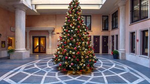 A large Christmas tree in a hotel lobby with a geometric tile floor and classical architecture. - River Palace Hotel (Rome)