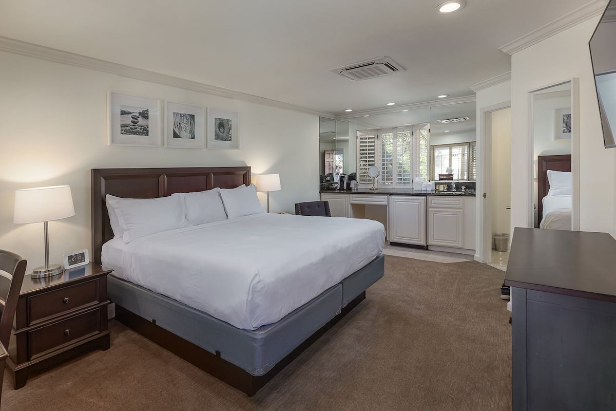 Une chambre d’hôtel avec un grand lit, des tables de chevet, un bureau et une kitchenette.