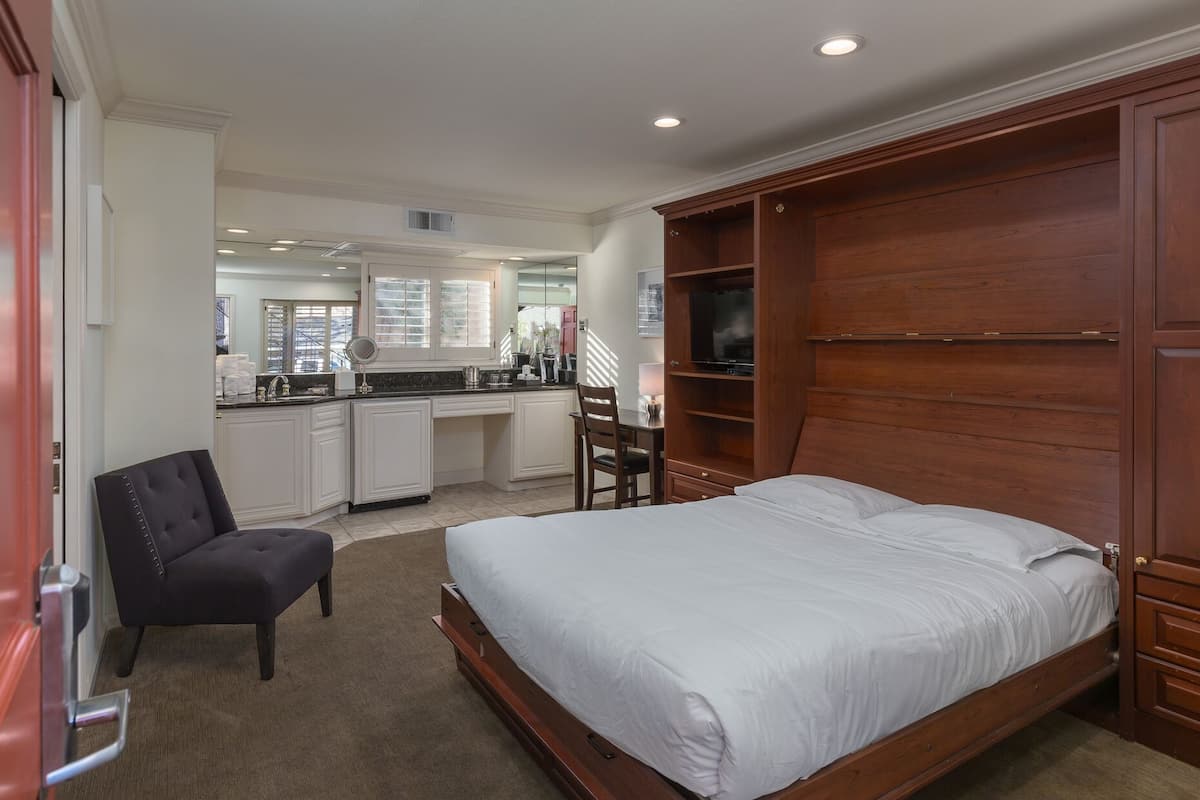 Une chambre à coucher avec un grand lit, une armoire en bois, un bureau et une chaise.