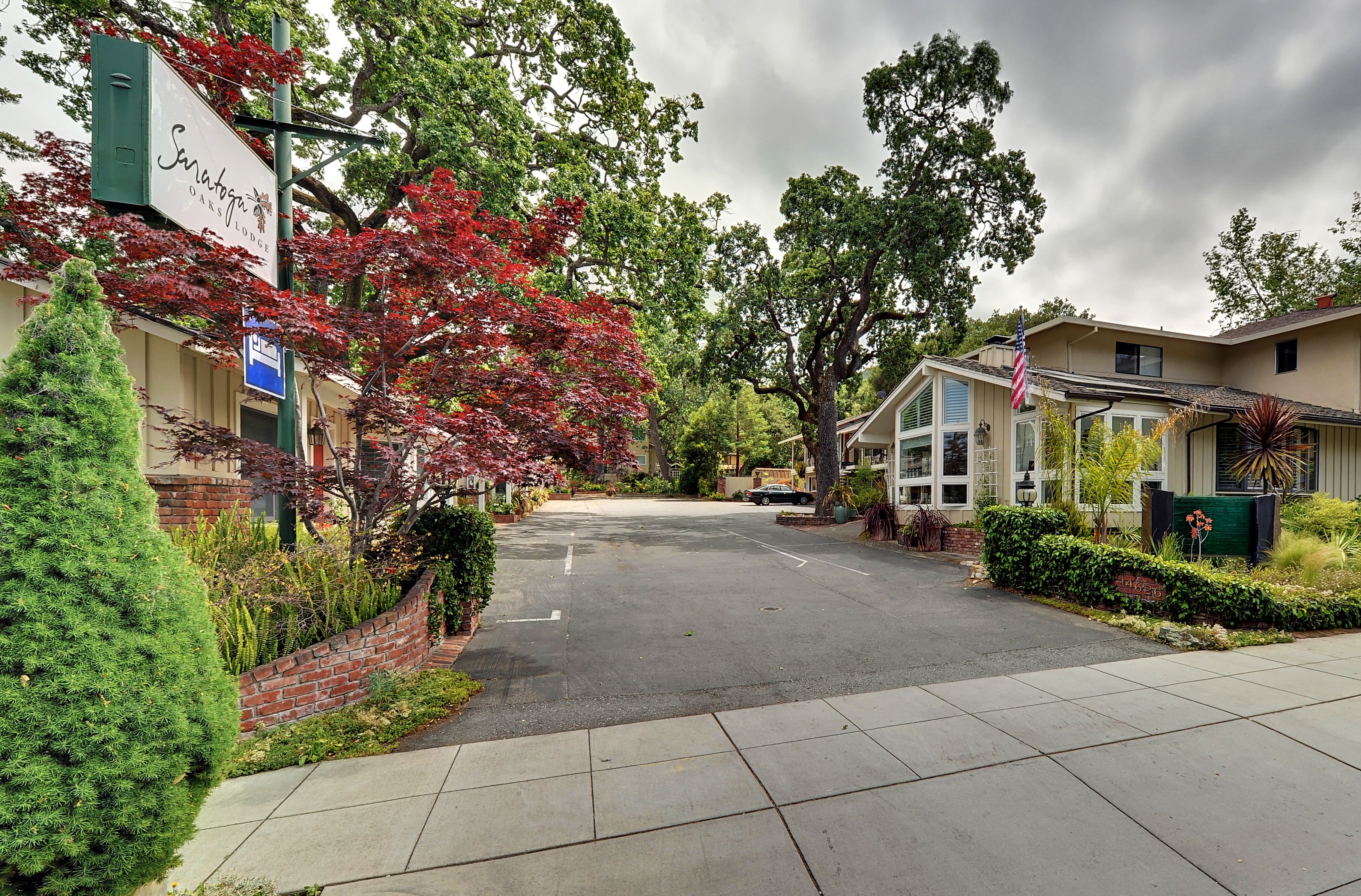 A quiet street with a hotel named 'Saratoga Inn & Suites' on the left, featuring a brick wall and greenery.