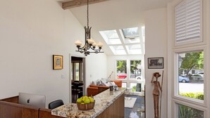 Une cuisine moderne avec un plan de travail en marbre, un îlot central en bois et un lustre.