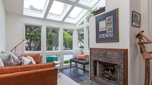 Un salon chaleureux avec une cheminée, de grandes fenêtres et un coin salon confortable.