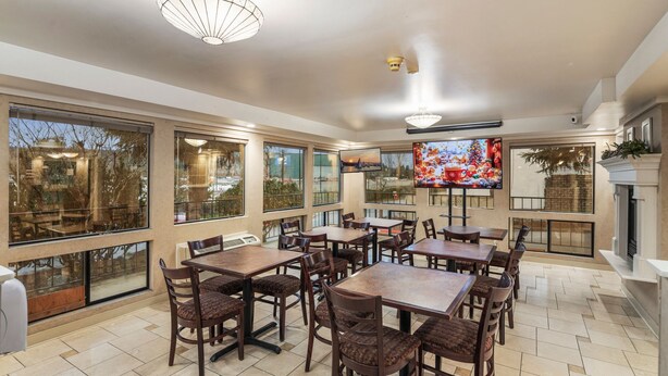 A spacious indoor dining area with multiple tables and chairs, large windows, and a fireplace.