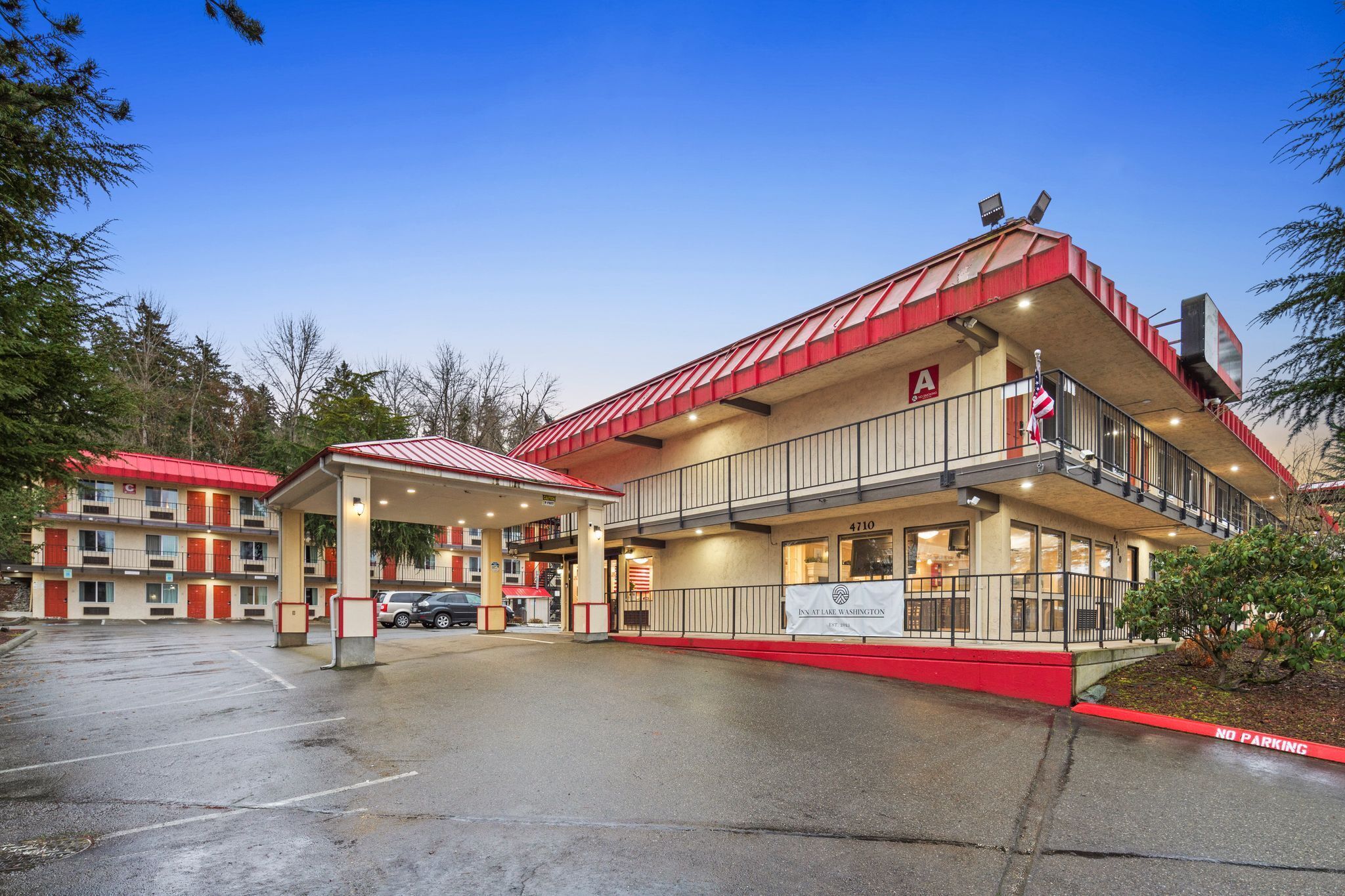 A motel with a red roof and a 'No Parking' sign.